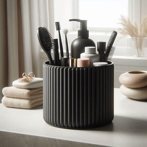 Può includere: Un organizer cilindrico grigio scuro e scanalato contiene vari accessori per il bagno. Gli articoli includono una spazzola per capelli, uno spazzolino da denti, pennelli per il trucco, un pettine e un dosatore di sapone. Sono visibili altri oggetti, tra cui asciugamani piegati e anelli decorativi.