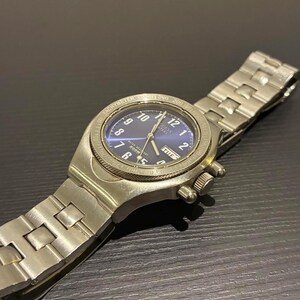 May include: A silver wristwatch with a blue face and silver hands. The watch has a stainless steel strap and a round face with numbers and markers. The watch also has two small dials and a date display.
