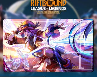 May include: A rectangular playmat for the League of Legends trading card game. The mat features a vibrant illustration of a female character with pink hair and a hat, surrounded by energy effects. The text "RIFTBOUND LEAGUE OF LEGENDS TRADING CARD GAME" is displayed at the top.