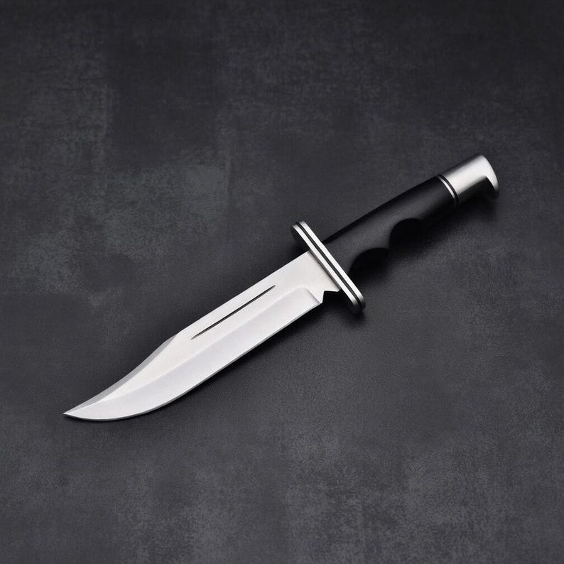 May include: A stainless steel hunting knife with a black handle and a silver bolster. The blade is sharp and curved, with a single fuller. The knife is designed for outdoor use and survival.