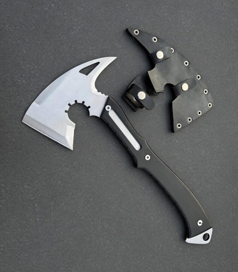 May include: A silver and black hatchet with a curved blade and a black handle. The hatchet has a protective black leather sheath with silver rivets. The hatchet is designed for outdoor use.