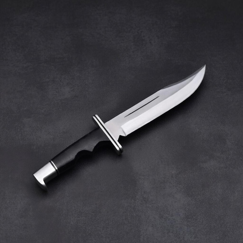 May include: A stainless steel hunting knife with a curved blade and a black handle. The knife features a silver bolster and a silver end cap. The blade is highly polished, reflecting the light. The knife is designed for outdoor use.