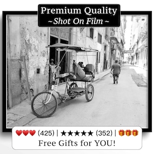 Puede incluir: Fotografía en blanco y negro de una escena callejera con un bicitaxi. Una persona está sentada en el taxi y otra camina por la calle. La imagen está enmarcada con un borde negro e incluye el texto "Premium Quality ~ Shot On Film ~."