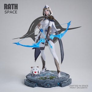 Puede incluir: Figura blanca y dorada de una arquera con arco y flecha azules, de pie sobre una base de piedra. La figura tiene una capucha y capa blancas. Una pequeña criatura blanca con una galleta en forma de corazón está a sus pies. El texto "RATH SPACE" y "CRAFTED IN SPACE PRINT ON EARTH" son visibles.
