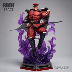 Puede incluir: Figura detallada de un personaje musculoso con uniforme rojo con detalles negros, gorra roja y cinturón. La figura está posada dinámicamente, rodeada de energía púrpura translúcida. La base es gris y roja, con el texto "RATH SPACE" y "CRAFTED IN SPACE PRINT ON EARTH."