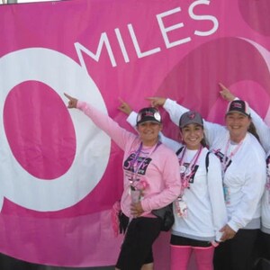 Puede incluir: Cuatro mujeres con camisas y sombreros rosas posan frente a una pancarta rosa con el texto "30 MILES".