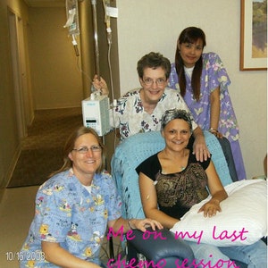 Puede incluir: Una mujer en una cama de hospital con una manta azul y una almohada. Lleva una camisa con estampado negro y dorado y una cubierta de cabeza blanca. Dos mujeres m&aacute;s est&aacute;n de pie detr&aacute;s de ella, una con una camisa morada y la otra con una camisa blanca y azul. El texto "Me on my last chemo session" est&aacute; escrito en la imagen.