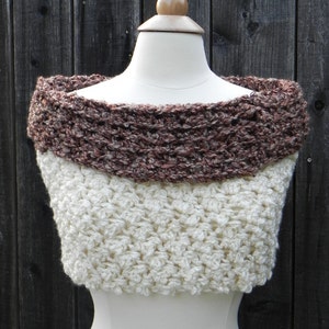 Puede incluir: Un cuello de punto de ganchillo en color marr&oacute;n y blanco. El cuello est&aacute; hecho con un punto texturizado y tiene un escote amplio y abierto.