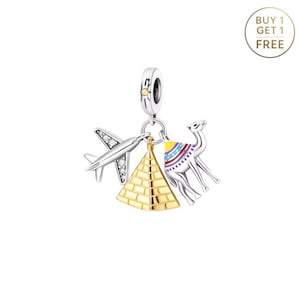 May include: A silver charm with travel-themed pendants. The charm features a plane with clear accents, a gold pyramid, and a camel with colorful details. The charm is designed to be attached to a bracelet or necklace.