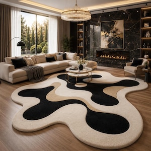 May include: A modern living room featuring a large, abstract-shaped rug with black, beige, and cream sections. The room includes a beige sectional sofa, a marble-topped coffee table, and a fireplace with a marble accent wall. A large window offers a view of the outdoors.