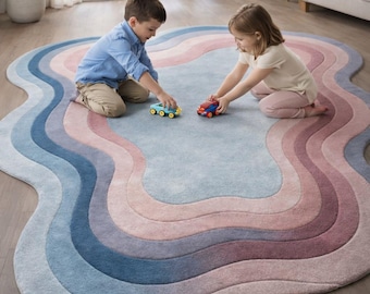 May include: A colorful, wavy-edged rug in shades of blue, pink, and purple. Two children are playing with toy cars on the rug. The rug's design resembles a series of layered, undulating waves, creating a soft and inviting space.