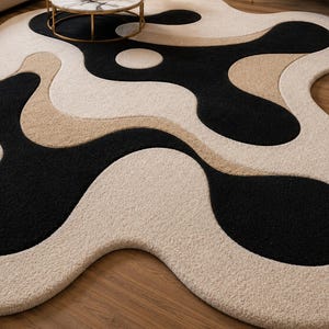 May include: A modern area rug with an abstract design. The rug features a flowing pattern of black, beige, and cream colors. The rug's unique shape and color palette create a contemporary aesthetic, suitable for living rooms or bedrooms.