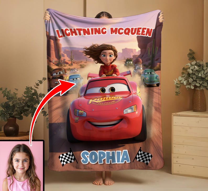Może przedstawiać: Czerwony koc Lightning McQueen z kresk&oacute;wkowym wizerunkiem postaci z filmu Auta. Koc ma imię "Sophia" i wz&oacute;r w szachownicę. Koc jest trzymany przez osobę.