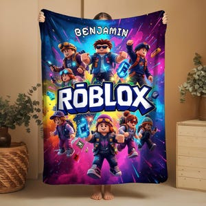 May include: A vibrant, colorful blanket featuring a Roblox theme. The blanket displays multiple Roblox characters in action poses against a dynamic, space-themed background. The name "BENJAMIN" is printed at the top, and the Roblox logo is prominently displayed.