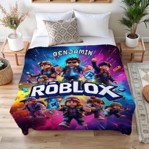 May include: A colorful Roblox-themed blanket featuring multiple animated characters in action poses. The blanket has a vibrant background with the Roblox logo and the name "BENJAMIN" displayed prominently. The design is set against a backdrop of blues, purples, and pinks.
