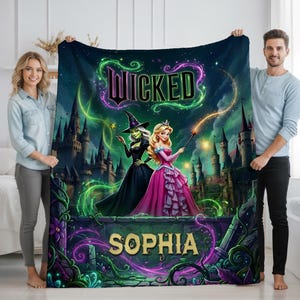 Peut inclure: Une couverture personnalisée avec une scène fantastique. Le mot "Wicked" est écrit en vert et violet. Le motif comprend deux personnages, une sorcière et une princesse, avec un château en arrière-plan. Le nom "Sophia" est affiché en bas.