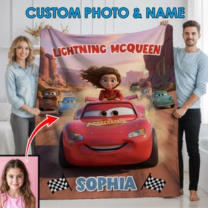 Może przedstawiać: Spersonalizowany koc z Zygzakiem McQueen z filmu Auta. Koc ma czerwony wz&oacute;r samochodu wyścigowego z imieniem "Sophia" i tekstem "Lightning McQueen". Tło przedstawia pustynny krajobraz.