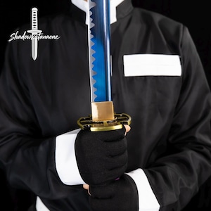 May include: A blue katana sword with a gold hilt and a black handle. The sword has a serrated edge and is held by a person wearing a black outfit with white accents. The text "ShadowKatanaone" is in the upper left corner.