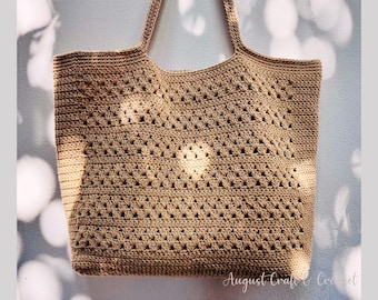 Peut inclure: Un sac fourre-tout beige en crochet avec deux anses. Le sac présente un motif ajouré avec un motif répétitif en forme de losanges. Le texte "August Craft & Crochet" est visible en bas à droite.