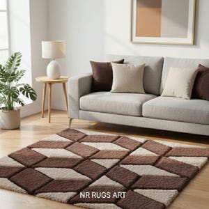 Op de afbeelding: Een rechthoekig tapijt met een geometrisch patroon in bruine en beige tinten. Het ontwerp heeft herhalende ruitvormen. De tekst "NR RUGS ART" is zichtbaar op het tapijt. Een grijze bank met kussens en een ingelijst kunstwerk staan op de achtergrond.
