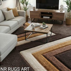 Op de afbeelding: Woonkamer met een geometrisch patroon tapijt in bruin, beige en crème tinten. Het tapijt is het middelpunt, aangevuld met een lichtgrijze bank, een houten salontafel en een grote flatscreen-tv. De tekst "NR RUGS ART" is zichtbaar.