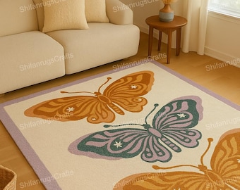Puede incluir: Una alfombra rectangular crema con borde lavanda, con tres grandes diseños de mariposas en naranja, verde y morado. La alfombra está colocada en un salón con un sofá y una mesa auxiliar.