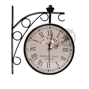 May include: A black, double-sided railway clock with Roman numerals and the text "VICTORIA STATION LONDON." The clock is mounted on a decorative black metal bracket. The clock hands are black and gold.