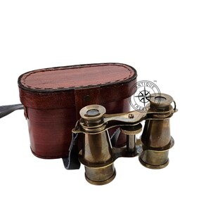 K&ouml;nnte beinhalten: Antike Operngl&auml;ser aus Messing mit einem braunen Lederetui. Das Fernglas hat ein klassisches Design mit Fokuseinstellung und wird von einer passenden Ledertragetasche mit Riemen begleitet. Das Etui ist oval geformt.