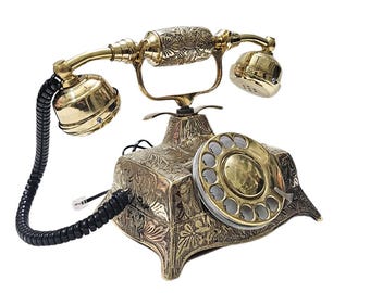 Könnte beinhalten: Ein antikes Drehscheibentelefon aus Messing mit aufwendigen floralen Gravuren. Das Telefon verfügt über einen Hörer, eine Wählscheibe und einen Sockel mit detaillierten Mustern. Das Spiralkabel ist schwarz. Es ist ein dekorativer Artikel.