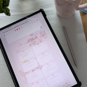 Könnte beinhalten: Ein schwarzes Tablet mit einem digitalen Planer namens Day Life Reset mit rosa Blumenmotiven, dazu ein schlanker Eingabestift, eine hellrosa Tasse mit Flamingomustern und Tee sowie eine Glasvase mit grünen Pflanzenstängeln.
