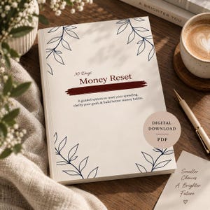 Könnte beinhalten: Ein cremefarbenes Buch mit dem Titel 30 Days Money Reset und dunkelblauen Blattillustrationen in den Ecken. Das Cover zeigt eine dunkelrote Pinselstrichgrafik und Text, der ein System zur Ausgabenkontrolle und zum Aufbau besserer Finanzgewohnheiten beschreibt.