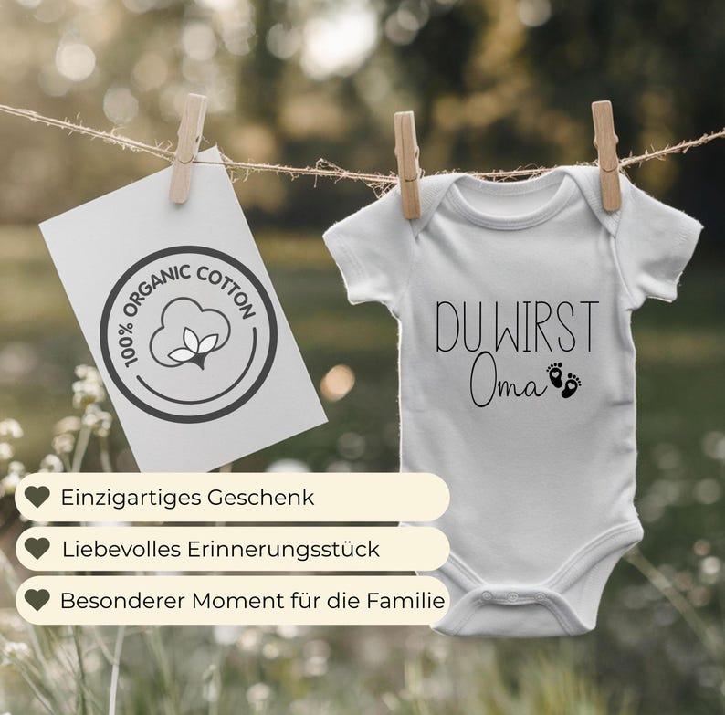 May include: A white baby onesie with the text "DU WIRST Oma" and tiny footprints. A card with "ORGANIC COTTON" text and a cotton flower logo hangs nearby. The image also shows text in German: "Einzigartiges Geschenk", "Liebevolles Erinnerungsst&uuml;ck", and "Besonderer Moment f&uuml;r die Familie".