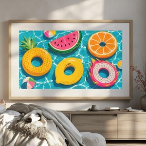 Könnte beinhalten: Ein gerahmter Wandkunstdruck mit einer lebendigen Illustration verschiedener fruchtförmiger Pool-Schwimmringe, darunter eine Ananas, eine Wassermelone, eine Orange, eine Zitrone und eine Drachenfrucht, die auf blauem Wasser schwimmen.