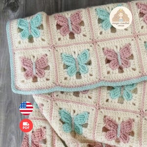 May include: A crochet blanket featuring a grid of square panels, each containing a raised butterfly motif in alternating pastel pink and light blue yarn. The background of each square is cream-colored, and the blanket is finished with a light blue scalloped border. A circular logo in the corner reads magic crochet.