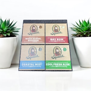 May include: A display of four Dr. Squatch men's natural soaps in a black display stand. The soap varieties include Wood Barrel Bourbon, Bay Rum, Coastal Mist, and Cool Fresh Aloe. Each soap weighs 5 oz (141 g).