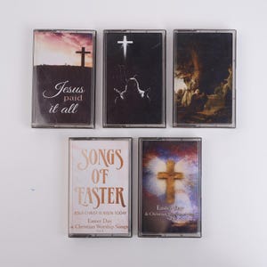 Puede incluir: Una colección de cinco cintas de casete con temas religiosos. Las cintas presentan imágenes de cruces, figuras religiosas y textos como "Jesus paid it all" y "Songs of Easter". Las carcasas de las cintas son transparentes.