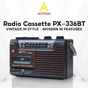 May include: A vintage-style radio cassette player with a brown wood-grain finish and black accents. The radio features a tuning dial, buttons, and the text "Radio Cassette PX-336BT VINTAGE IN STYLE - MODERN IN FEATURES". It includes a handle for portability.