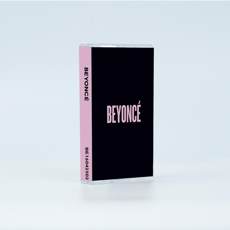 May include: A cassette tape with a black cover featuring the word BEYONC&Eacute; in light pink lettering. The side spine is light pink with the word BEYONC&Eacute; printed in black vertically, followed by the alphanumeric code BE16042502 in black text.