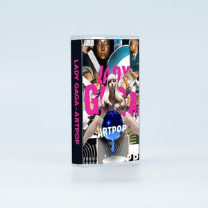 May include: A cassette tape case featuring the Lady Gaga Artpop album cover. The artwork displays a collage of images including a central figure with blonde hair holding a blue sphere, with the text LADY GAGA and ARTPOP printed in pink and white.