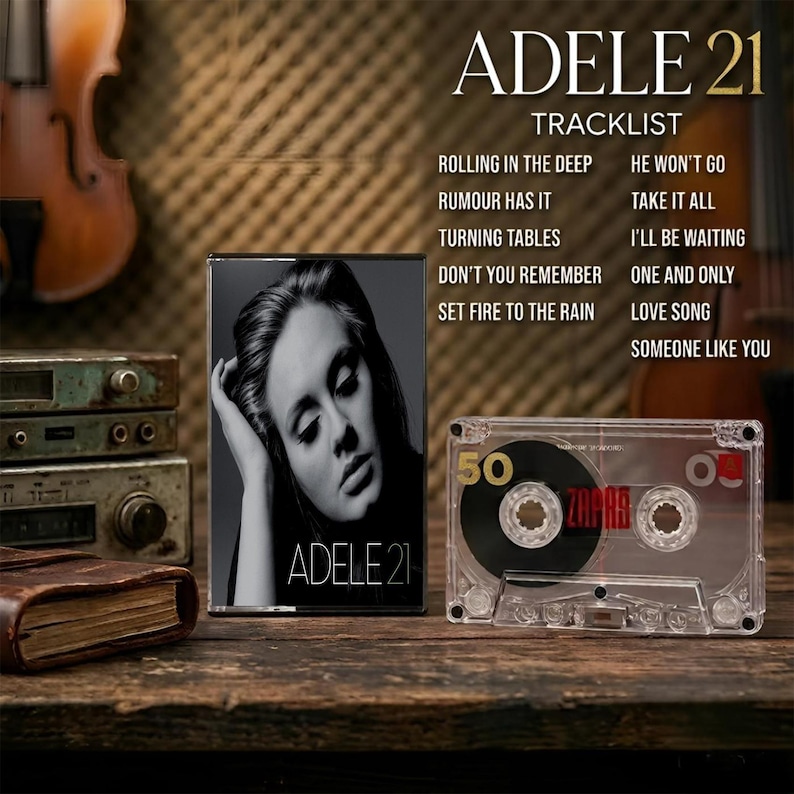 May include: A black and white Adele 21 album cover featuring a portrait of the artist, alongside a clear plastic cassette tape with the number 50 and the word ZAPAR printed on it. The tracklist includes Rolling in the Deep and Someone Like You.