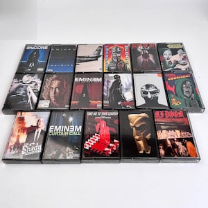 Op de afbeelding: Een verzameling vintage cassettebandjes met albumhoezen. De bandjes tonen verschillende artiesten en albumtitels, waaronder "Encore", "Infinite" en "The Shady Project". De kunstwerken tonen een reeks kleuren en stijlen, met portretten en abstracte ontwerpen.