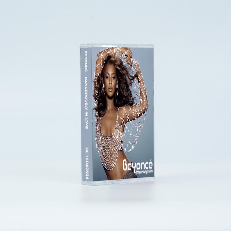 May include: A cassette tape case featuring the album Dangerously in Love by Beyonc&eacute;. The cover art displays a photograph of the artist wearing a silver beaded top. The text Beyonc&eacute; and Dangerously in Love is printed on the front and side.