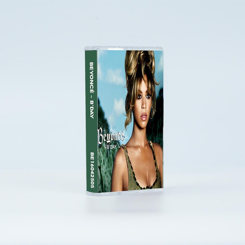 May include: A rectangular cassette tape case featuring the album B'Day by Beyonc&eacute;. The cover art displays a portrait of Beyonc&eacute; against a blue sky and green foliage. The spine is dark green with the text BEYONC&Eacute; - B'DAY and BE 16042505 printed.