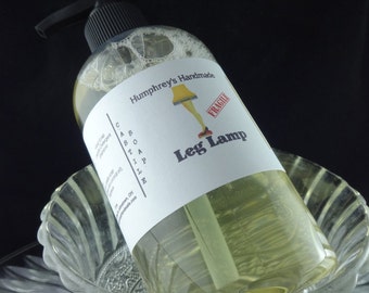 Può includere: Una bottiglia trasparente di sapone liquido con un erogatore a pompa nero. L'etichetta è bianca con testo nero che recita "Humphrey's Handmade Castile Soap" e un'immagine di una lampada con le gambe. L'etichetta ha anche un timbro rosso che dice "Fragile" e le parole "Leg Lamp".