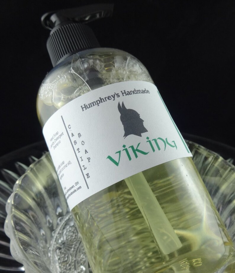 May include: A clear bottle of green liquid with a white label that says "Humphrey's Handmade Castile Soap Viking". The label also features a black silhouette of a Viking helmet.