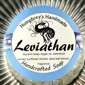 May include: A blue and white round soap label with the text "Humphrey's Handmade Leviathan Handcrafted Soap" and a black and white illustration of a mythical sea creature. The label lists the ingredients: glycerin soap, argan oil, calendula extract, sunflower extract, aloe leaf extract, and fragrance.
