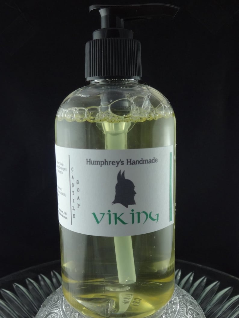 May include: A clear bottle of liquid soap with a black pump top. The label reads "Humphrey's Handmade Castile Soap Viking".