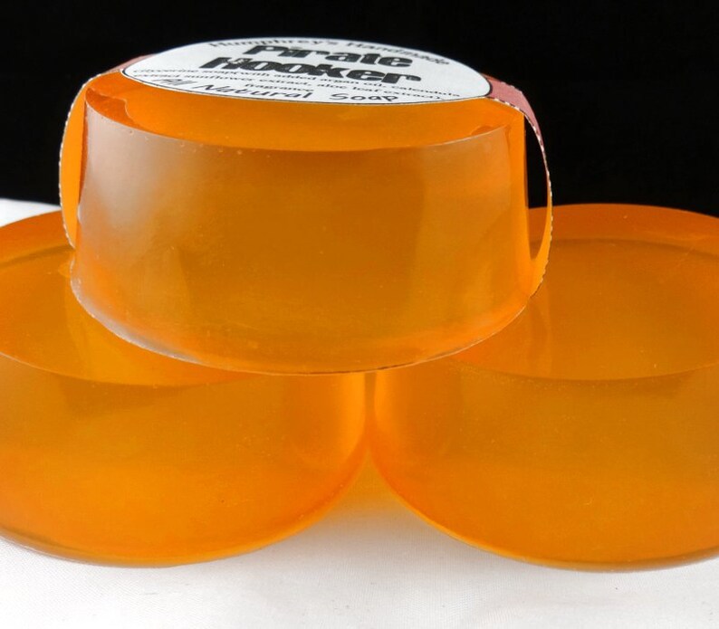 Pu&ograve; includere: Tre saponette artigianali di colore arancione impilate l'una sull'altra. La saponetta in cima ha un'etichetta che recita "Humphrey's Handmade Pale Hooker Soap - Natural".