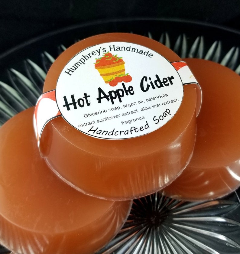 May include: Three round bars of handcrafted soap with a label that reads "Humphrey's Handmade Hot Apple Cider Glycerine soap, argan oil, calendula extract sunflower extract, aloe leaf extract, fragrance Handcrafted Soap".