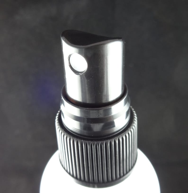 May include: Close-up of a black plastic spray bottle top with a white nozzle.